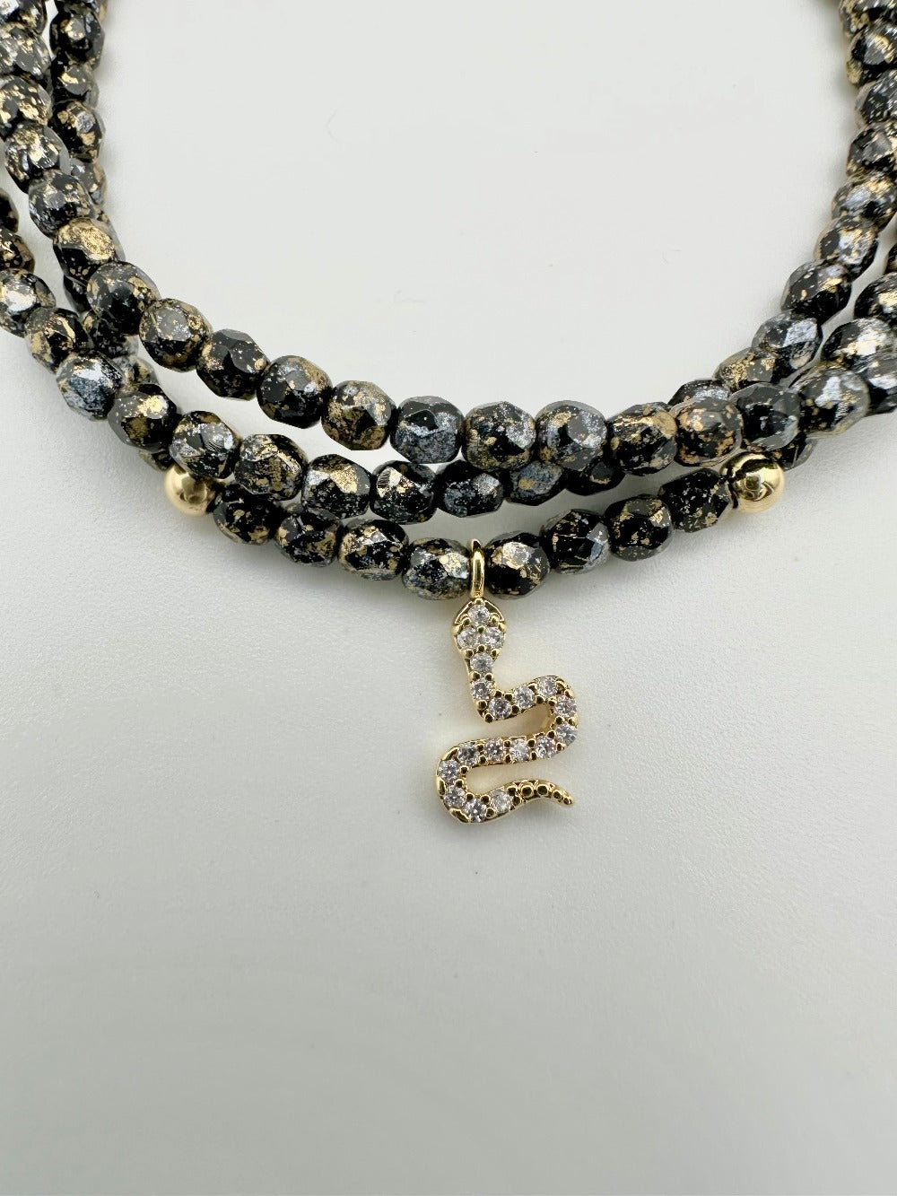 Ce bijou CaJouX est composé de facettes de Bohème couleur Noir et ça breloque Serpent doré et oxyde de zirconium.