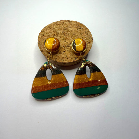 Boucle d'oreille en argile polymère avec du vert, du orange et du doré et du marron sur une base d'acier inoxydable.