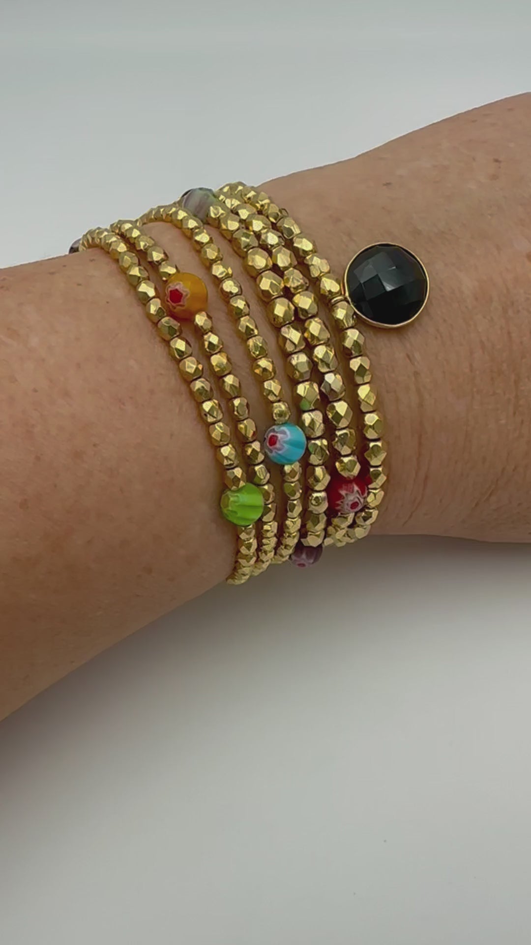 Ce bijou CaJouX est composé de facettes de Bohème couleur Or plaqué 24K sur un fil élastique de grande qualité. On y retrouve aussi des perles rondes Millefiori et ça breloque Onyx noir et plaqué Or.